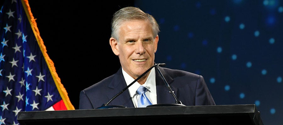 Rick-Pollack-smiling-at-podium-with-American-flag-background