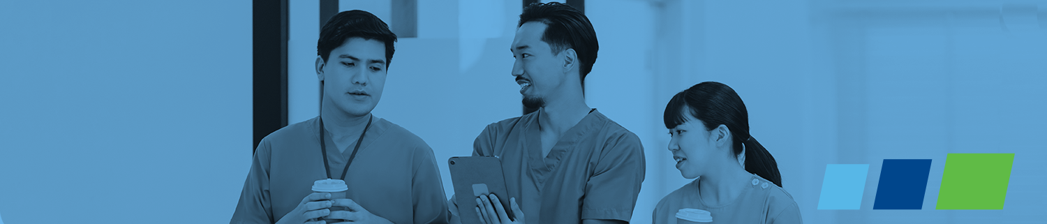 three health care professionals wearing scrubs talking and walking in hallway