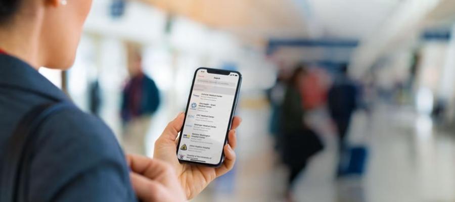 An health app user holds a mobile phone in his left hand and reviews app notifications.